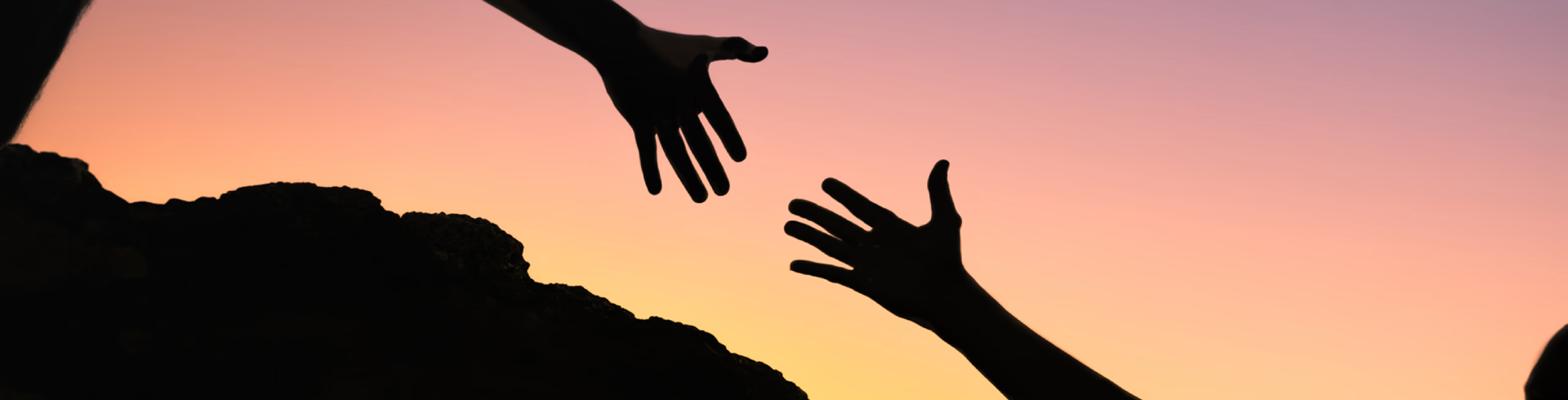 Two hands reaching toward each other at sunset